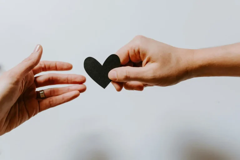 hands passing a paper heart to each other