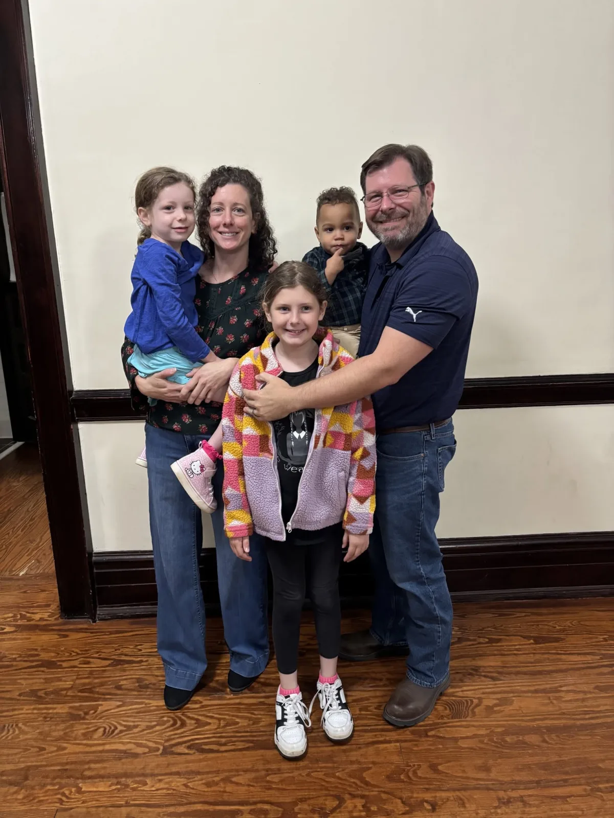 A foster family — two parents with three children — together on the day of their adoption